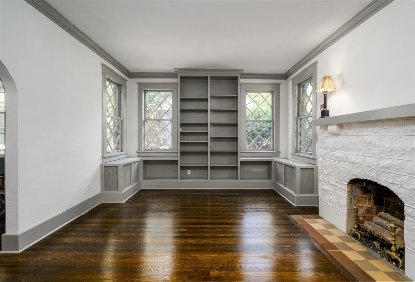 Unfurnished living room with arched walkways, ornamental molding, a fireplace, plenty of natural light, and dark wood-style floors
