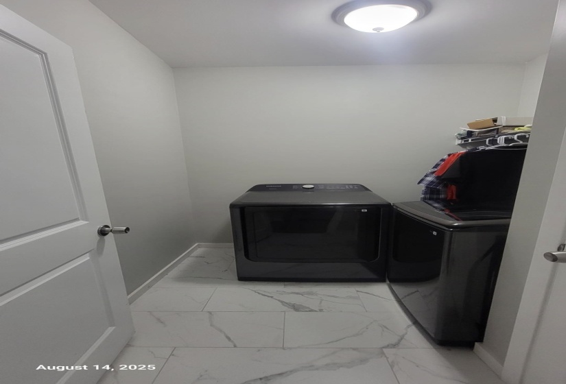 Laundry room featuring light marble finish flooring and separate washer and dryer