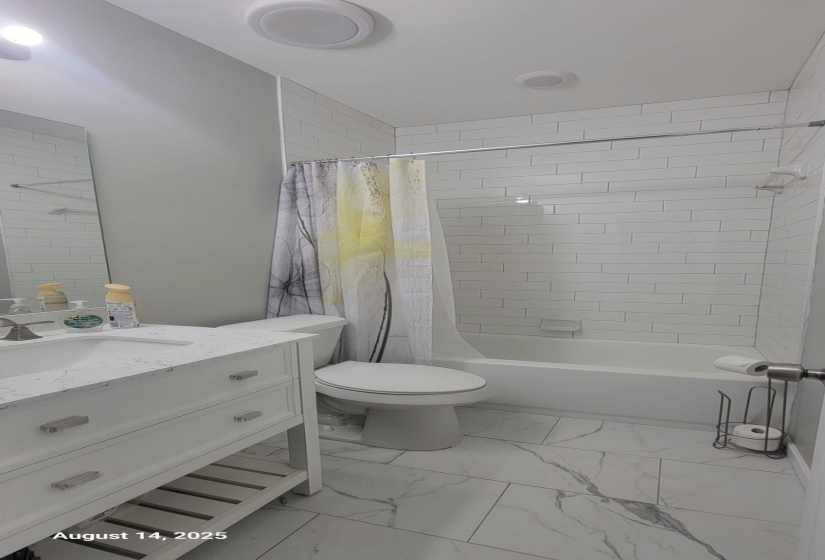 Full bathroom featuring shower / bath combo with shower curtain, vanity, and light marble finish flooring