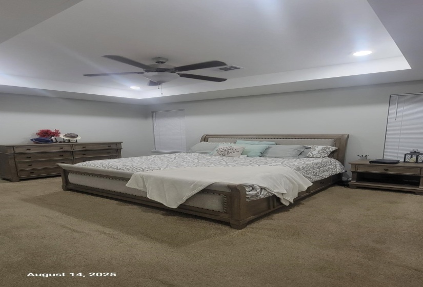 Bedroom featuring a raised ceiling, light colored carpet, recessed lighting, and a ceiling fan