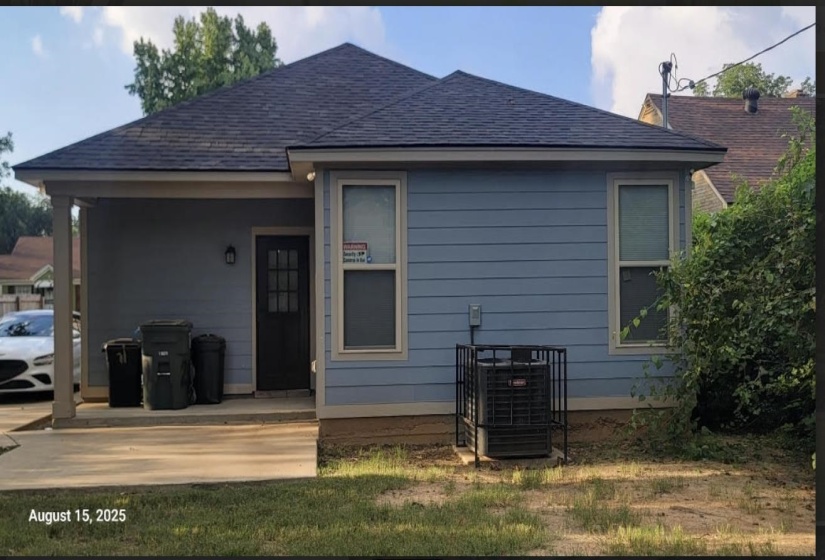 Back of property featuring a porch, roof with shingles, and a lawn