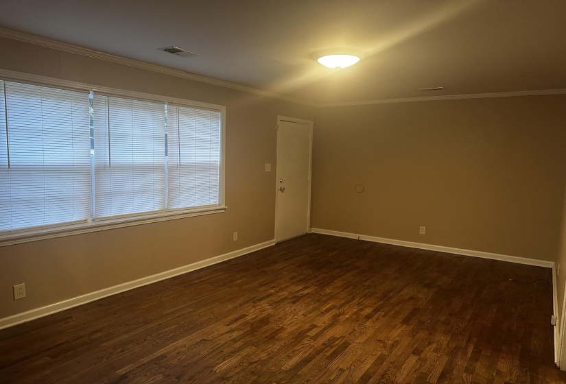 Spare room featuring ornamental molding and dark wood-type flooring