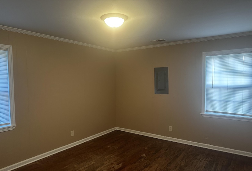 Empty room featuring dark wood finished floors, electric panel, and ornamental molding