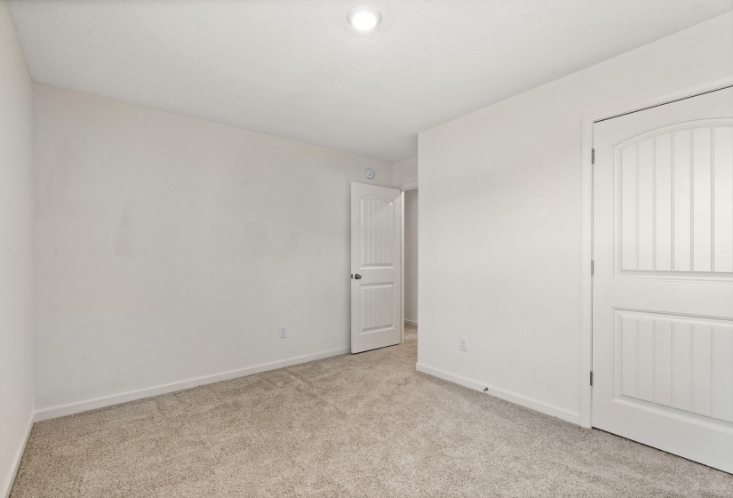 Unfurnished bedroom with light carpet and baseboards