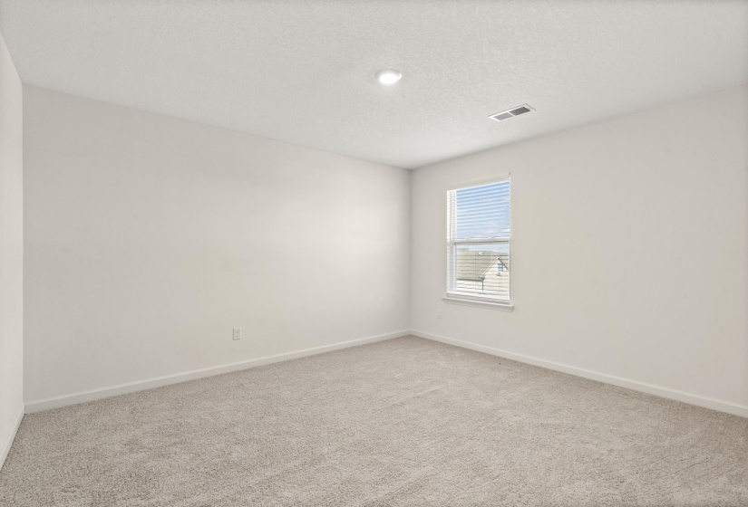 Empty room with light colored carpet and a textured ceiling