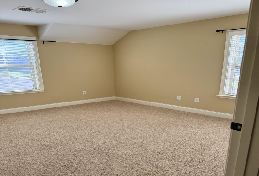Carpeted empty room featuring baseboards and vaulted ceiling