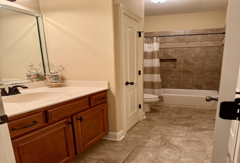 Full bathroom featuring vanity, shower / bath combo, and light stone finish floors
