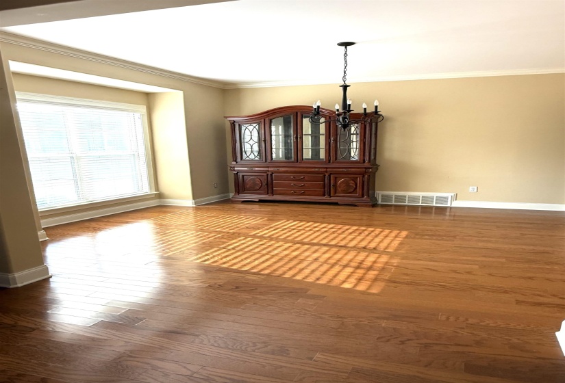 Empty room with ornamental molding, a chandelier, and hardwood / wood-style floors