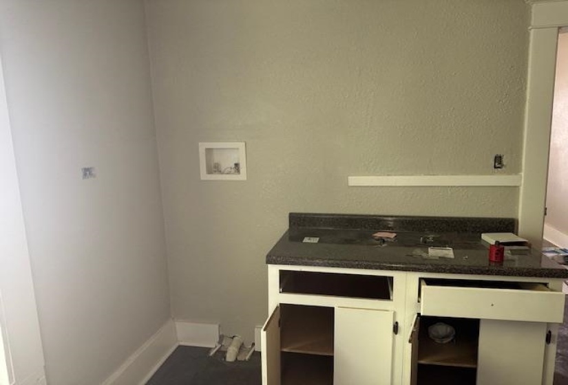 Kitchen featuring white cabinets, open shelves, and dark carpet