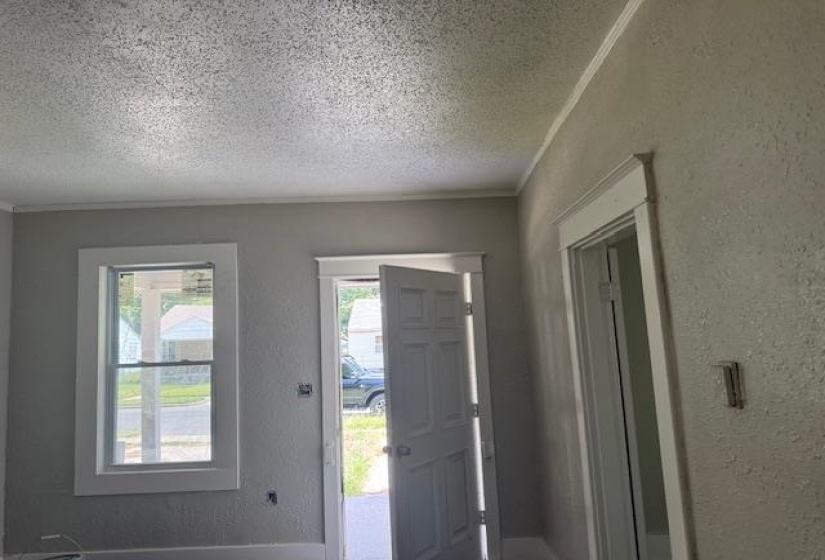 Entryway with a textured wall, a textured ceiling, and ornamental molding