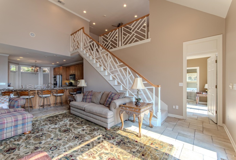 Living room featuring a high ceiling, stairway, recessed lighting, light tile patterned floors, and crown molding