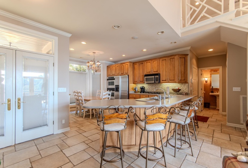Kitchen with a peninsula, a breakfast bar, crown molding, brown cabinetry, and french doors
