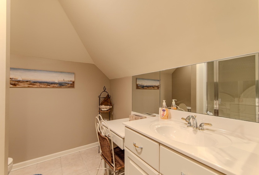 Full bathroom featuring vanity, light tile patterned flooring, vaulted ceiling, and a shower stall