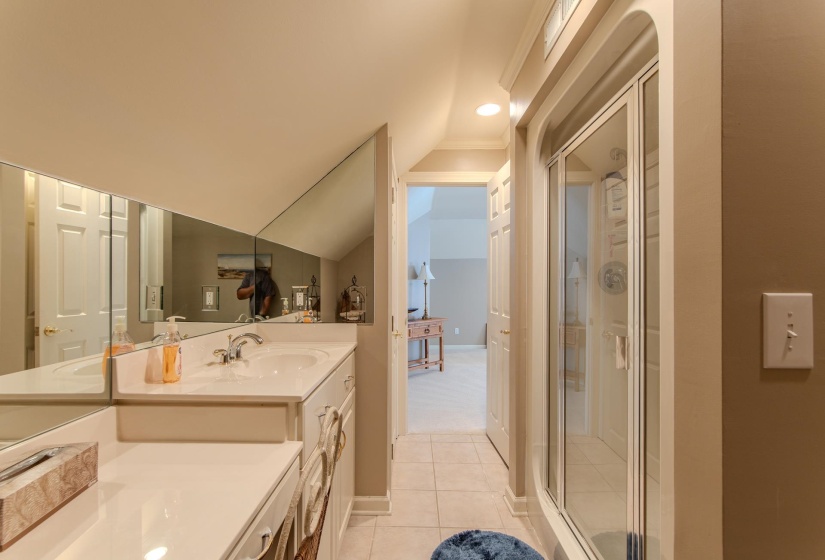 Bathroom with light tile patterned flooring, double vanity, a shower stall, vaulted ceiling, and recessed lighting