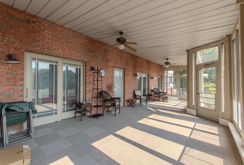 Sunroom / solarium featuring brick wall, a ceiling fan, carpet floors, and wood ceiling