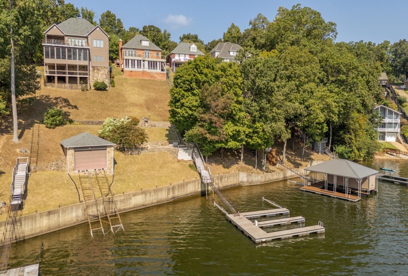 Dock featuring a residential view, boat lift, a water view, and view of scattered trees