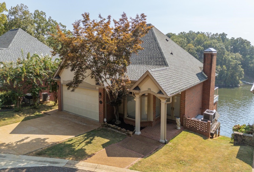 View of front of property with roof with shingles, brick siding, driveway, a chimney, and a garage