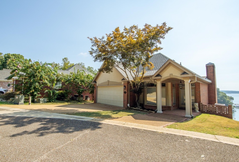 View of front facade featuring brick siding, a chimney, and driveway