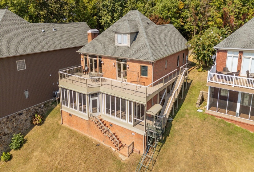 Back of house featuring a sunroom, a patio area, roof with shingles, and a yard