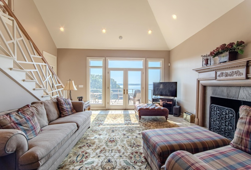 Living room featuring stairway, high vaulted ceiling, a tile fireplace, recessed lighting, and french doors