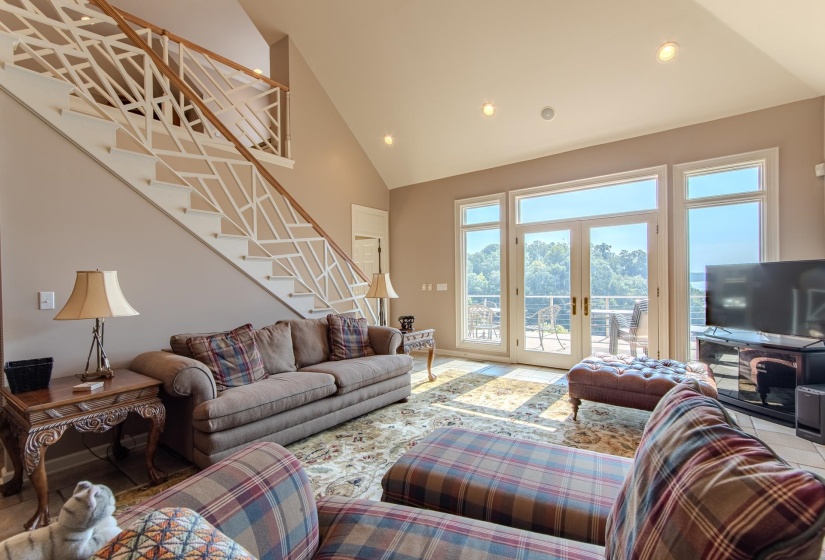 Living room featuring high vaulted ceiling, recessed lighting, stairs, and french doors