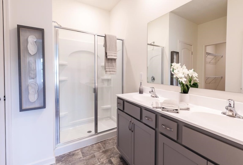 Full bathroom featuring a stall shower, double vanity, stone finish floors, and a spacious closet