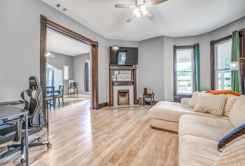 Living room with an office area, light wood-style floors, ceiling fan, and a tile fireplace