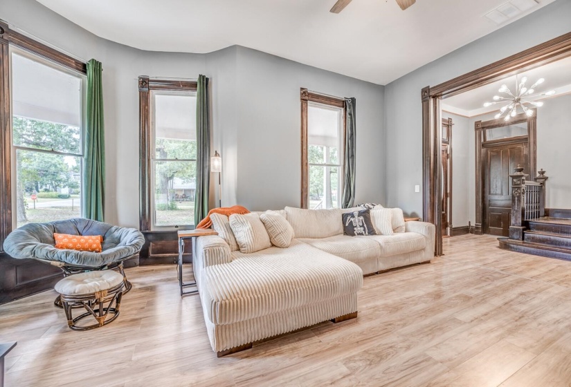Living room featuring wood finished floors, a ceiling fan, a chandelier, and stairway
