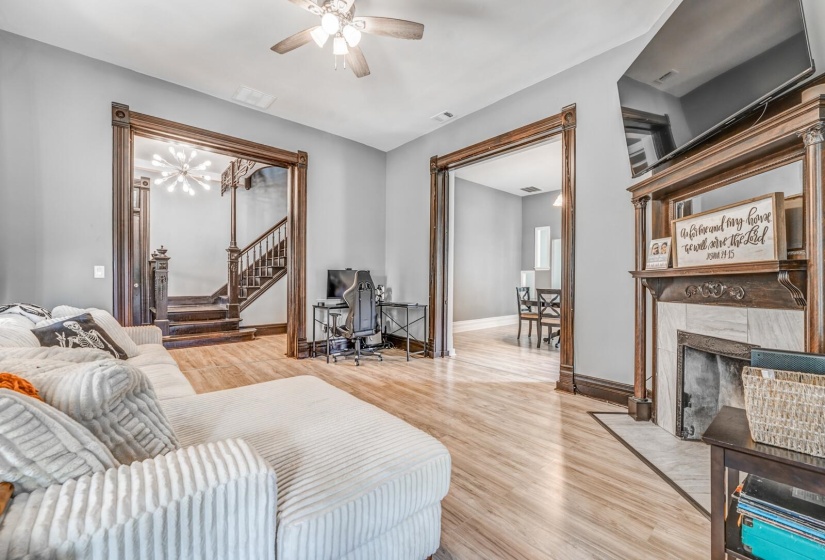 Living room featuring light wood-style floors, ceiling fan, a high end fireplace, and stairway