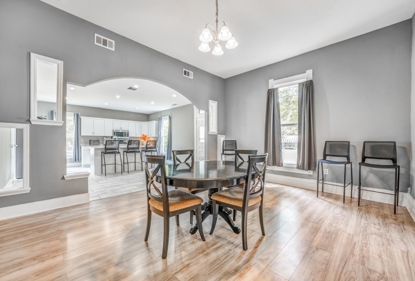 Dining room featuring arched walkways, light wood-type flooring, and a chandelier