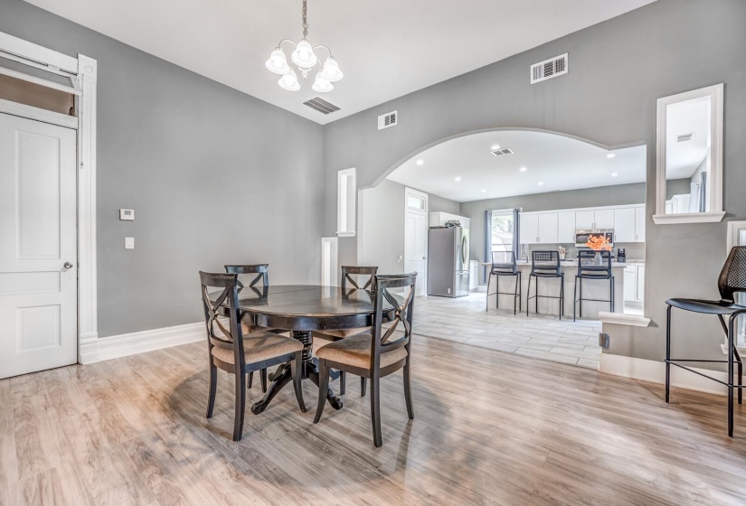 Dining area featuring light wood finished floors, a chandelier, and arched walkways