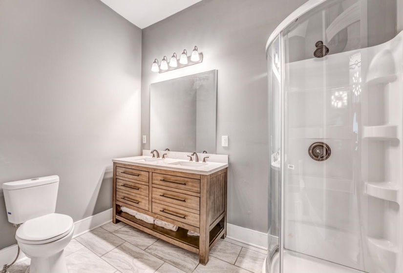 Full bath featuring a shower stall and double vanity