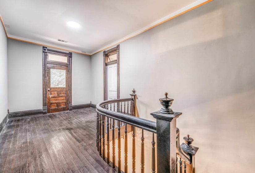 Hall with crown molding, dark wood-style floors, and an upstairs landing