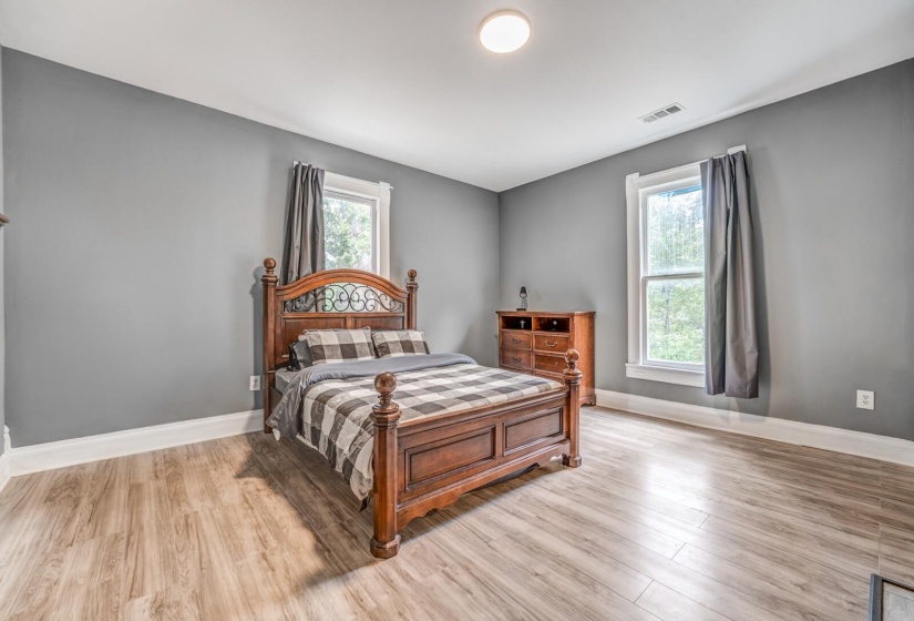 Bedroom with wood finished floors and multiple windows