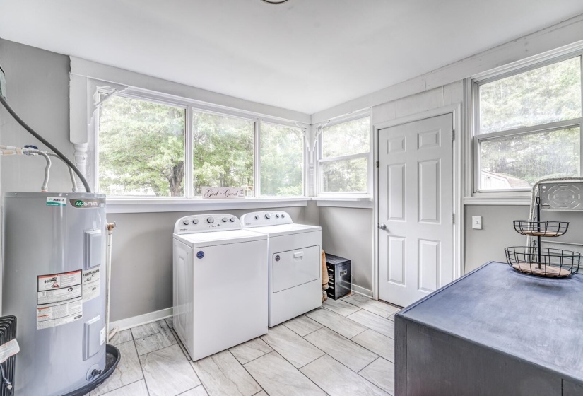 Laundry area featuring water heater, healthy amount of natural light, and washing machine and dryer