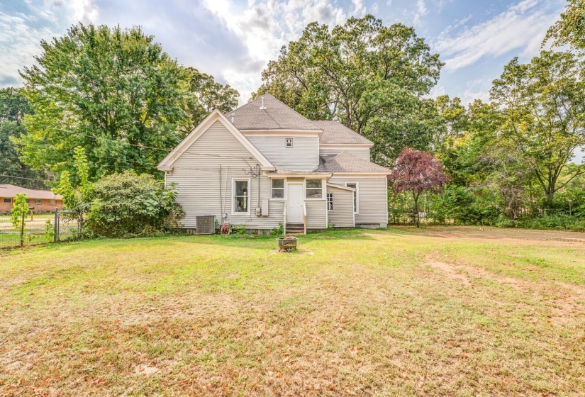 Back of house featuring a yard, roof with shingles, view of wooded area, and entry steps