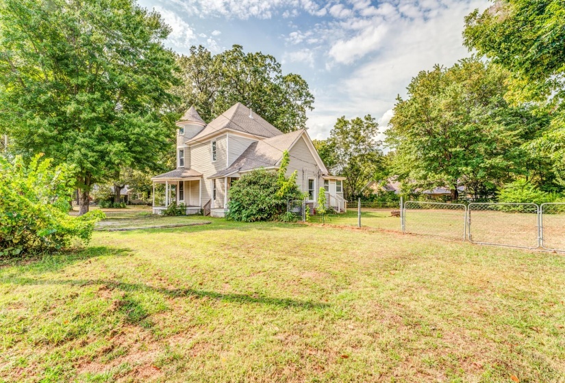View of home's exterior with a porch, view of wooded area, and a gate