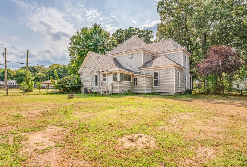 Rear view of property featuring a shingled roof and view of scattered trees