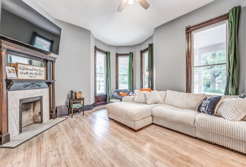 Living area featuring wood finished floors, healthy amount of natural light, a high end fireplace, and ceiling fan