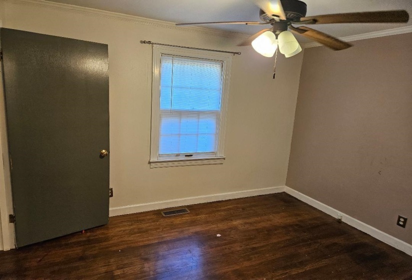 Unfurnished room with crown molding, dark wood-style flooring, and a ceiling fan