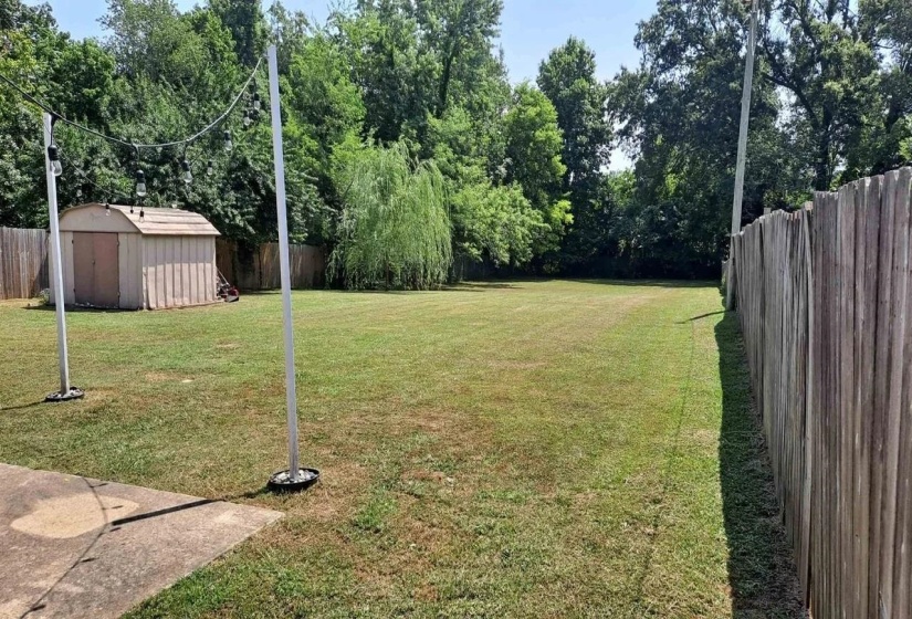 Fenced backyard featuring a shed