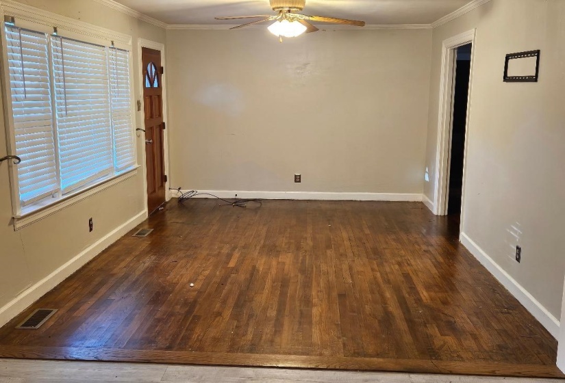 Unfurnished room featuring ornamental molding, dark wood-type flooring, and a ceiling fan