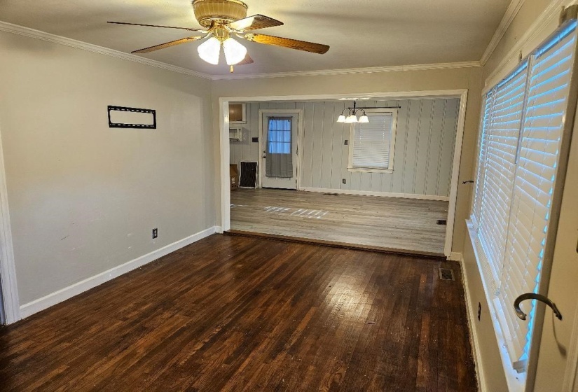 Unfurnished living room featuring dark wood-style floors, ornamental molding, a chandelier, and ceiling fan