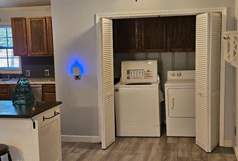 Laundry room featuring cabinet space, washing machine and dryer, light wood finished floors, and crown molding