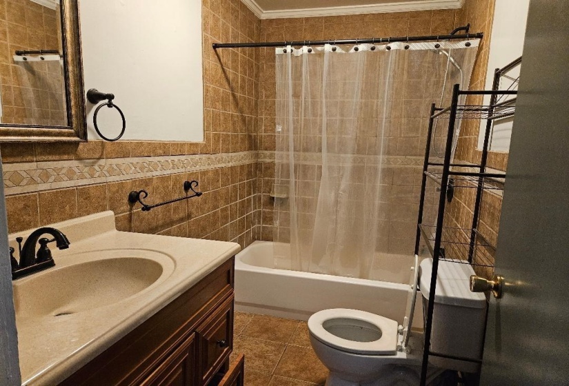 Bathroom featuring shower / bath combination with curtain, vanity, crown molding, tile walls, and dark tile patterned floors