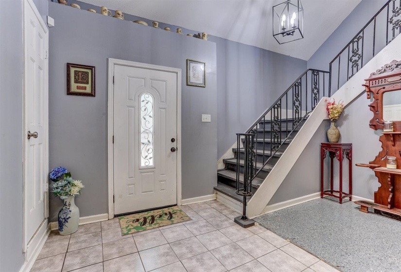 Entryway with light tile patterned floors and a chandelier