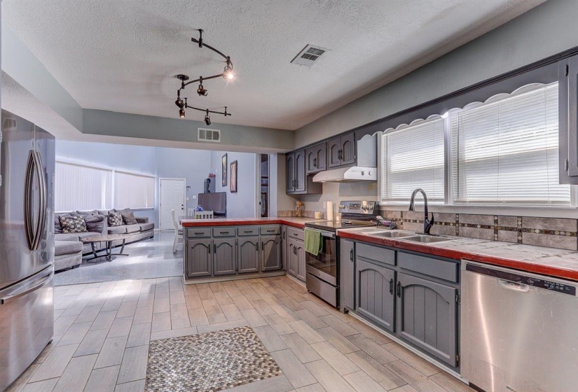 Kitchen featuring open floor plan, stainless steel appliances, gray cabinetry, a peninsula, and a textured ceiling