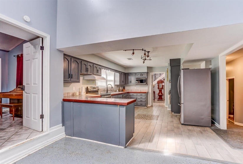 Kitchen featuring appliances with stainless steel finishes, tile counters, gray cabinets, a peninsula, and under cabinet range hood
