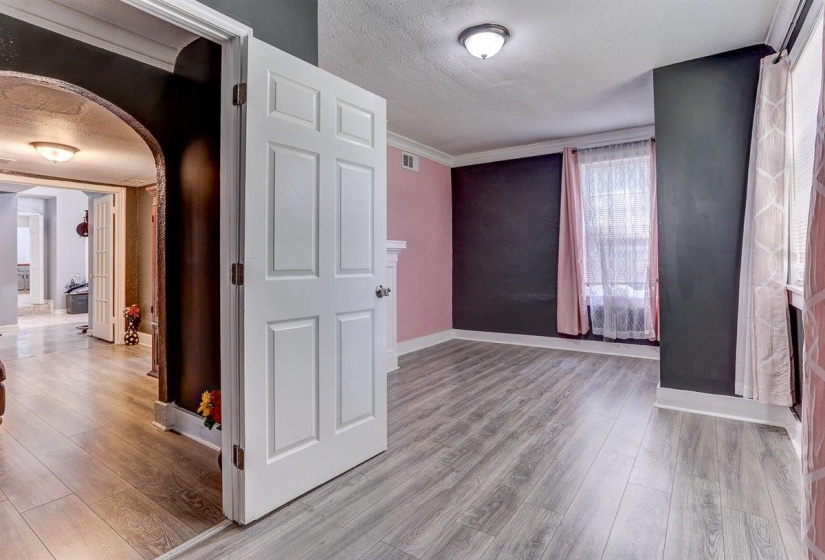 Hall featuring a textured ceiling, light wood-style floors, arched walkways, and crown molding