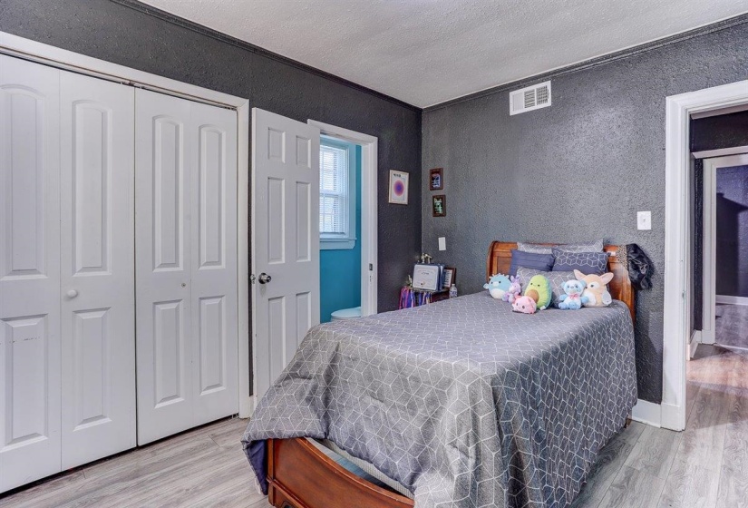 Bedroom with a closet, light wood-style flooring, a textured wall, and a textured ceiling